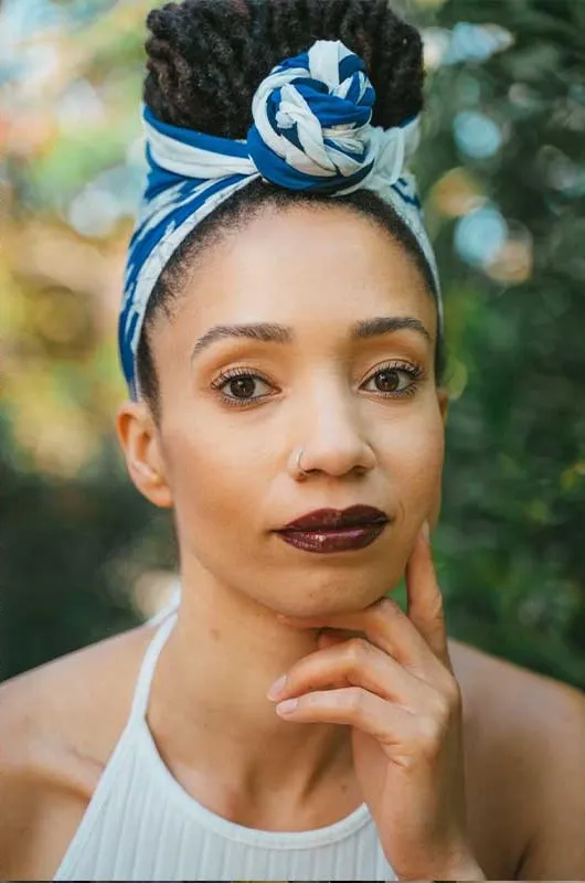 Dr. Ashley Alexis, smiling softly, outdoors in green garden light.